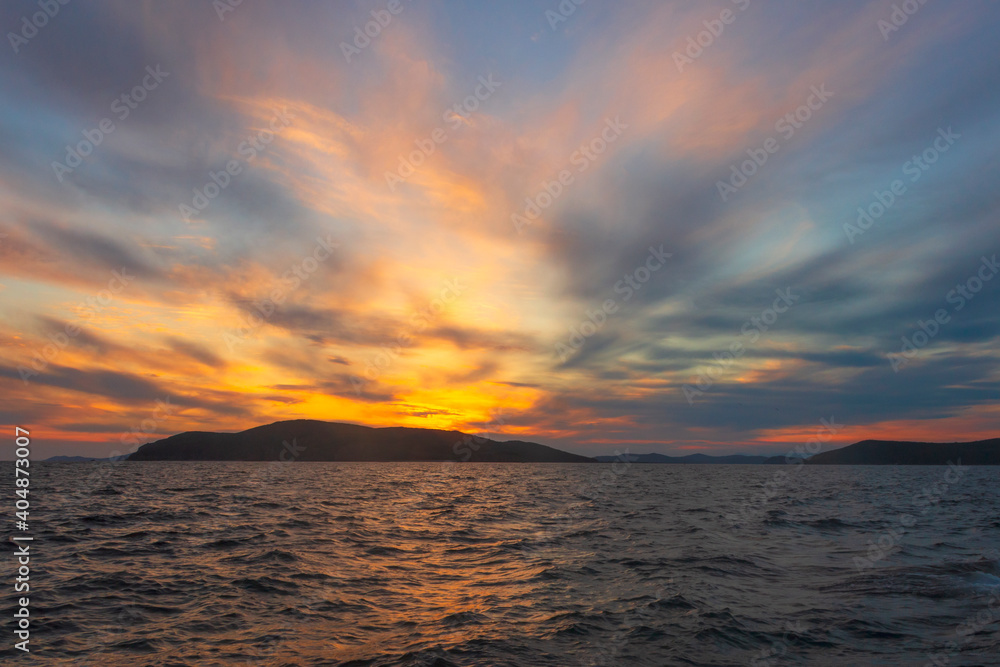 Obraz premium Picturesque sunset on the sea among the clouds on a summer evening. Tobisina Cape, Russian island, Vladivostok.