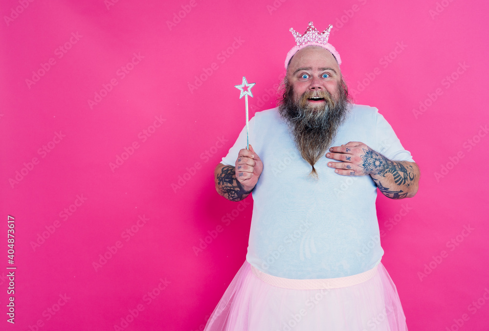 Fototapeta premium Funny man dancing and having fun wearing a ballet outfit. Happy princess on a pink colored background