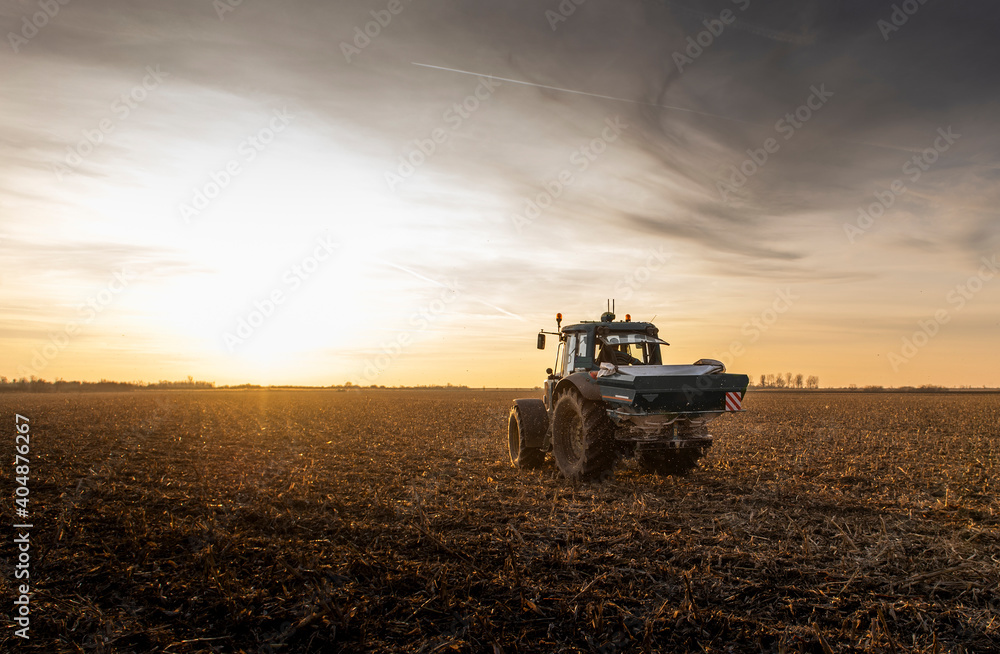Fototapeta premium Tractor spreading artificial fertilizers in field