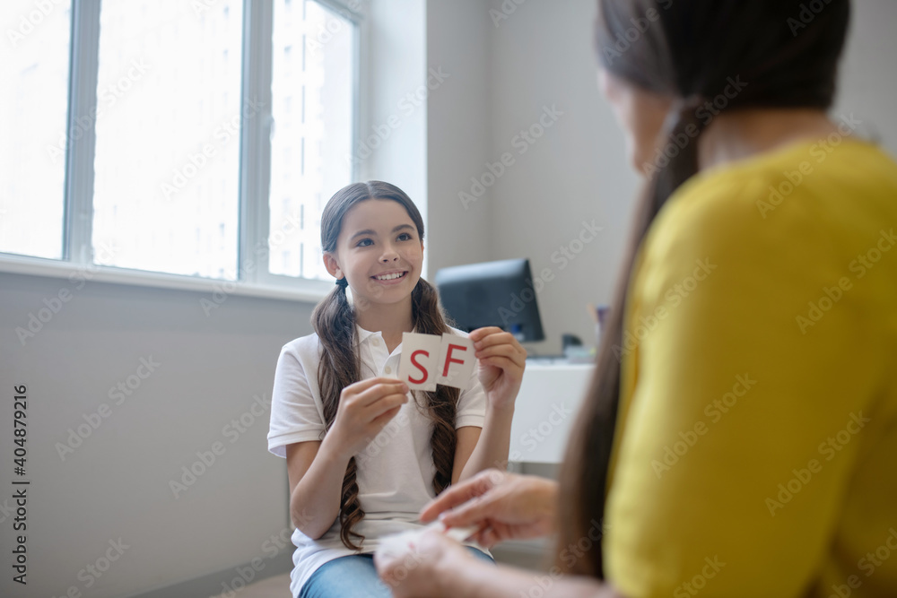 Smiling girl with cards and child psychologist Smiling girl with cards and child psychologist