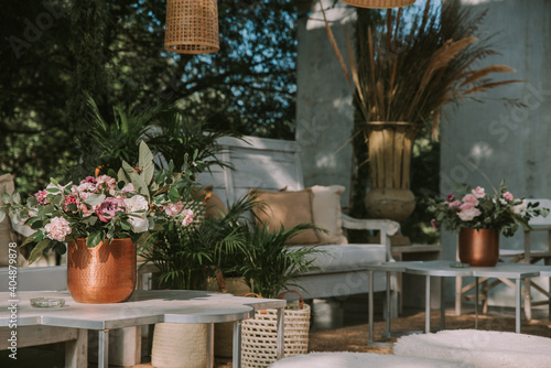 Armchairs and garden table adorned with pots  flowers and imitation leather fabrics.