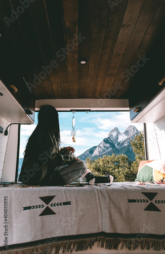 image of a young brunette woman, stretched out inside a camper van, looking towards Pedraforca mountain