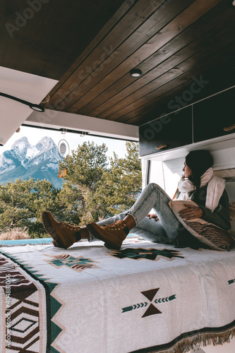 image of a young brunette woman, stretched out inside a camper van, looking towards Pedraforca mountain