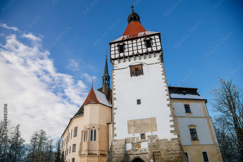Medieval renaissance water castle with half-timbered tower with snow in winter sunny day, Historic Romantic chateau Blatna near Strakonice in southern Bohemia, Czech Republic