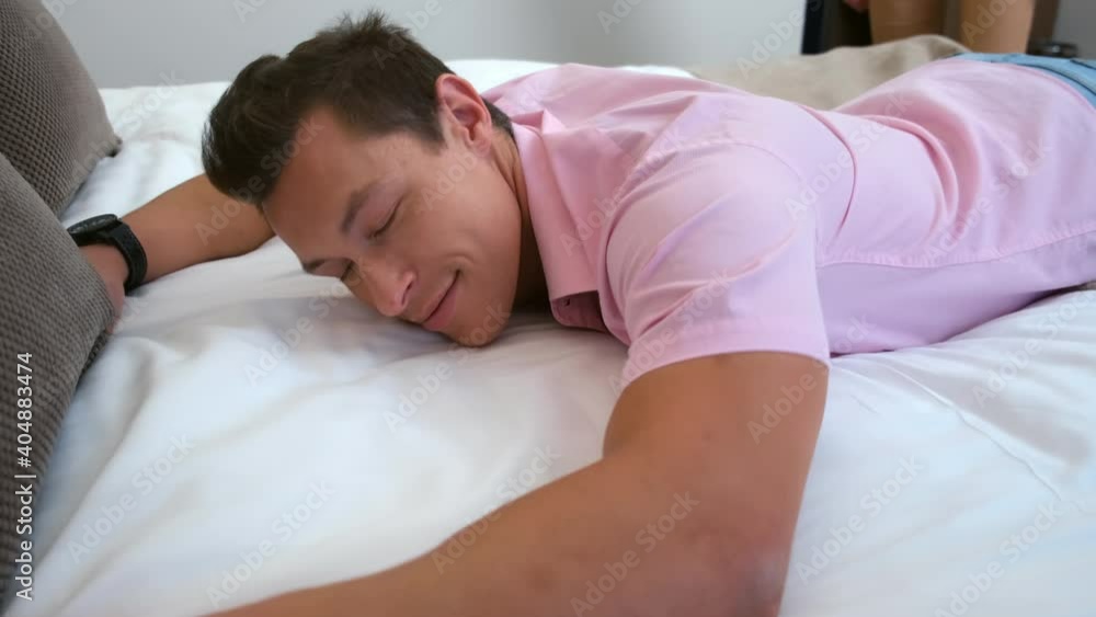 Man and woman are falling on the bed in hotel room, slow motion. Resting in resort spa hotel. Young couple in love are traveling together. They are cuddling lying in bed, woman gives a hugs to man. Man and woman are falling on the bed in hotel room, slow motion. Resting in resort spa hotel. Young couple in love are traveling together. They are cuddling lying in bed, woman gives a hugs to man.