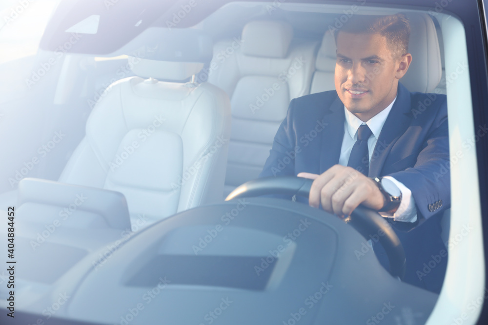 Handsome man driving his modern car, view from outside Handsome man driving his modern car, view from outside