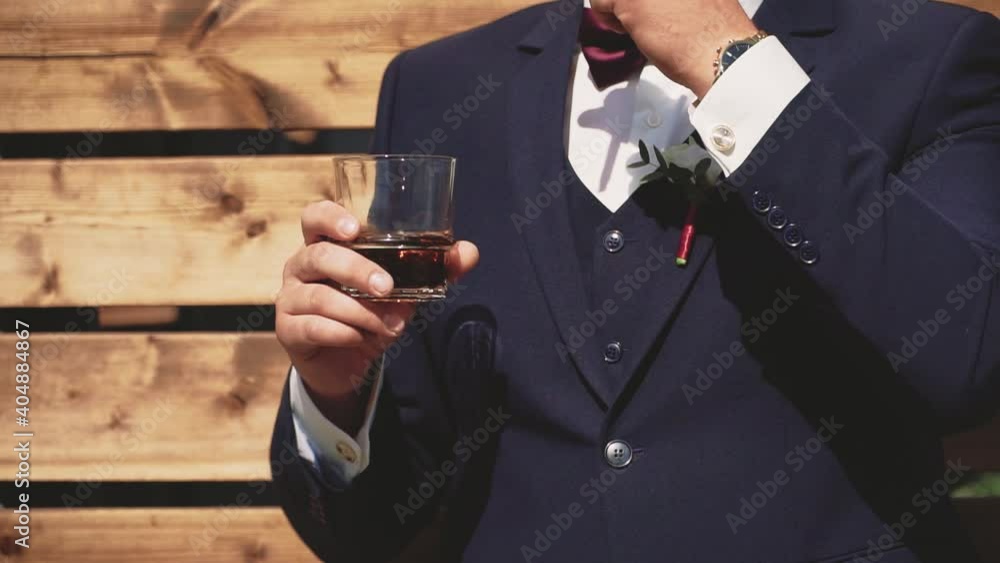 A man in a suit with a glass of whiskey in his hands A man in a suit with a glass of whiskey in his hands