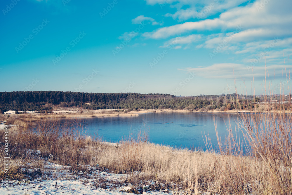 Lake in the middle of the forest with blue water on a sunny early spring day Lake in the middle of the forest with blue water on a sunny early spring day