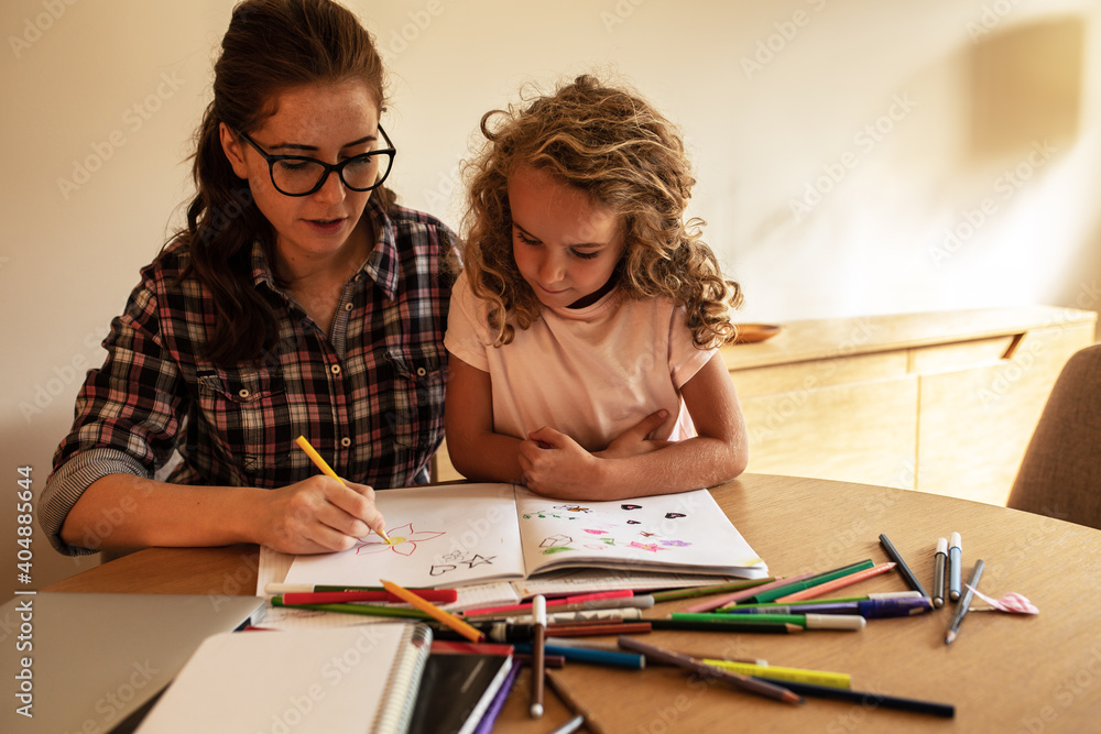 Mother helps her daughter to draw with colored pencils.
Mother helps her daughter to draw with colored pencils.