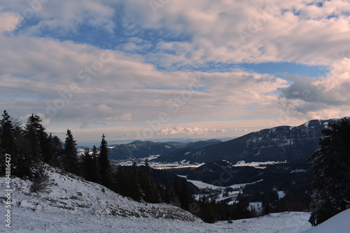  Schneelandschaft mit verschneiten verkrüppelten Bäumen im Gebirge vor blauem Himmel mit Wolken 