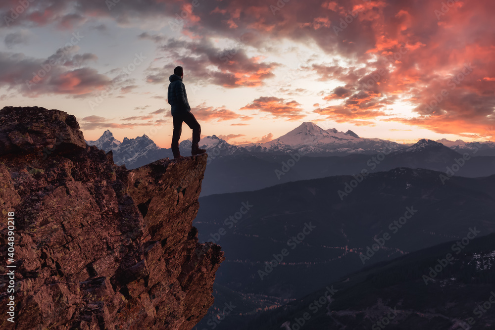 Fototapeta premium Adventurous man is standing on top of the mountain and enjoying the beautiful view. Taken on top of Cheam Peak in Chilliwack, East of Vancouver, BC, Canada. Colorful Sunset Sky Art Render