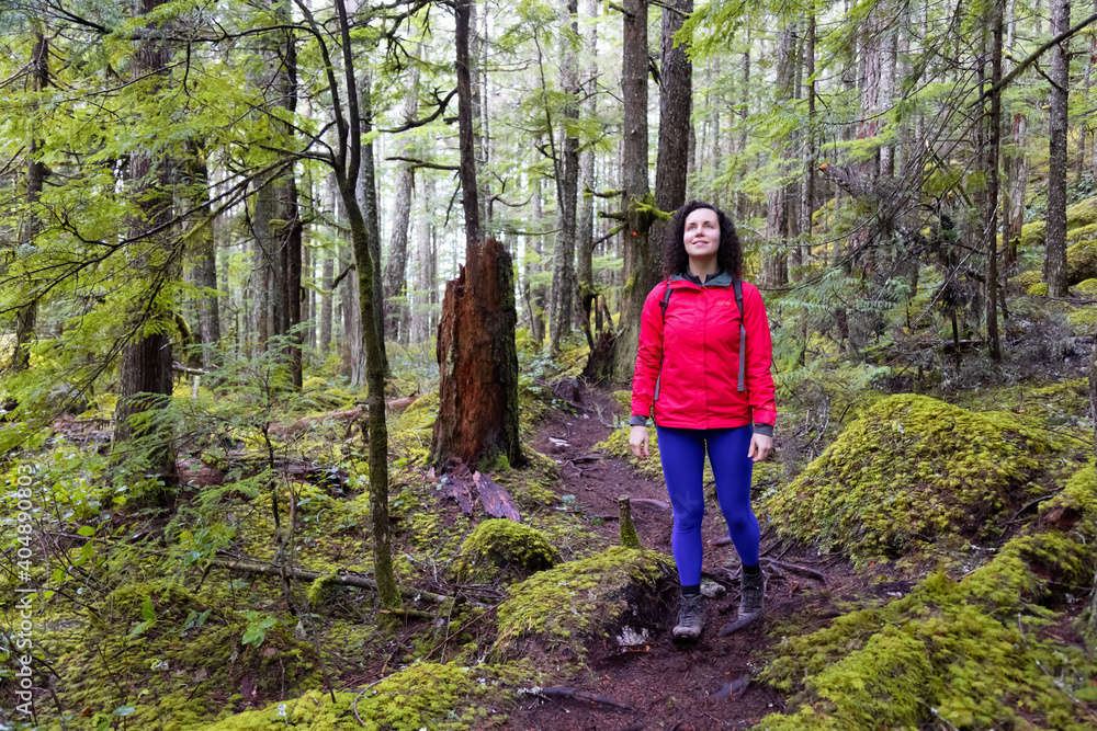 Girl Hiking on a Path in the Rain Forest during a rainy Winter Season. Squamish, North of Vancouver, British Columbia, Canada. Girl Hiking on a Path in the Rain Forest during a rainy Winter Season. Squamish, North of Vancouver, British Columbia, Canada.