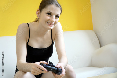 Junge Frau auf Sofa hat Spaß beim Spielen mit Controller und Konsole photo