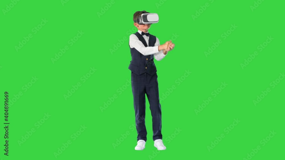 Excited boy in formal wear playing the sword game in virtual reality goggles on a Green Screen, Chroma Key. Excited boy in formal wear playing the sword game in virtual reality goggles on a Green Screen, Chroma Key.