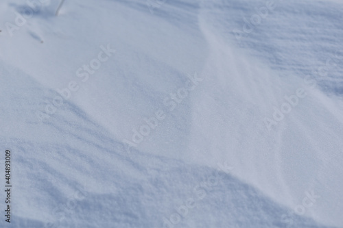 Vom Wind verwehte Schneeoberfläche mit Windstrukturen als winterlicher Hintergrund mit Naturschnee