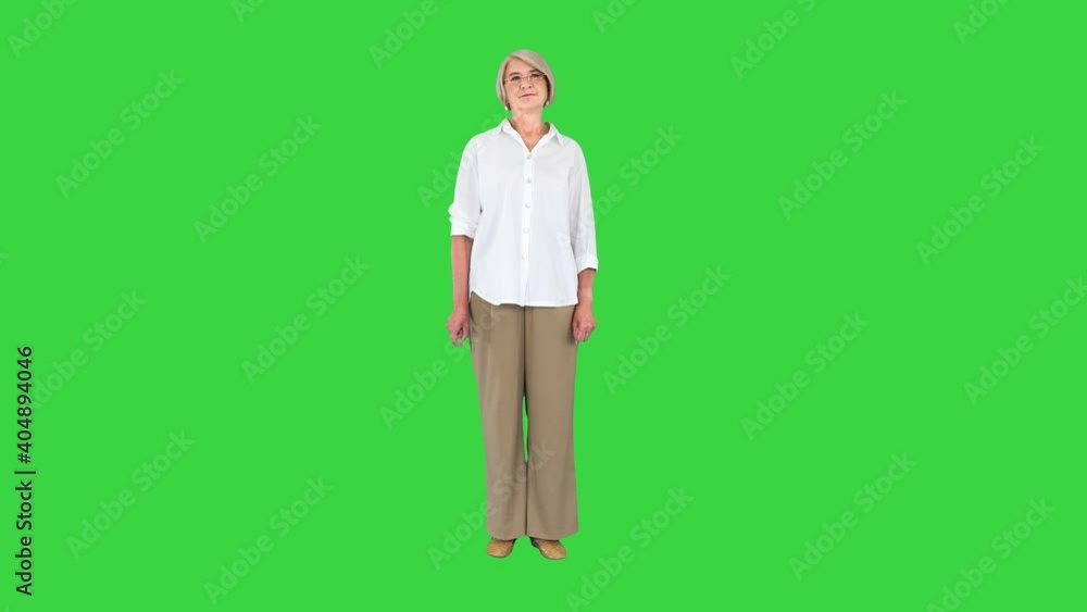 Aged Woman in White Shirt Standing Doing Nothing on a Green Screen, Chroma Key. Aged Woman in White Shirt Standing Doing Nothing on a Green Screen, Chroma Key.