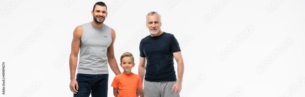 happy kid with grandpa and father in sportswear smiling at camera isolated on white, banner happy kid with grandpa and father in sportswear smiling at camera isolated on white, banner