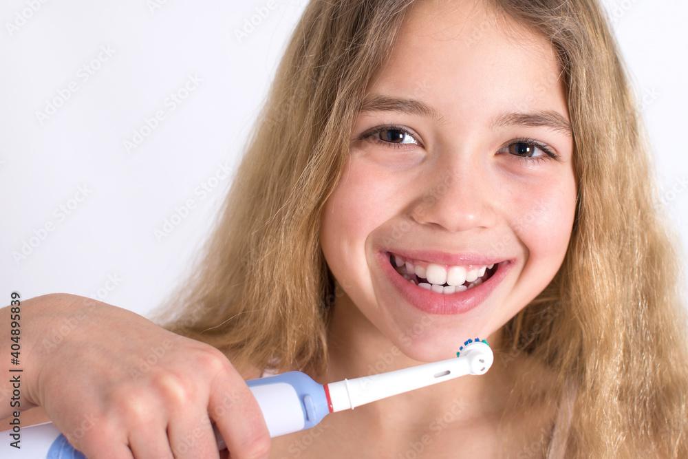 Young girl portrait with rotating-oscillating electric toothbrush isolated on white background. Oral hygiene and white teeth concept. Young girl portrait with rotating-oscillating electric toothbrush isolated on white background. Oral hygiene and white teeth concept.