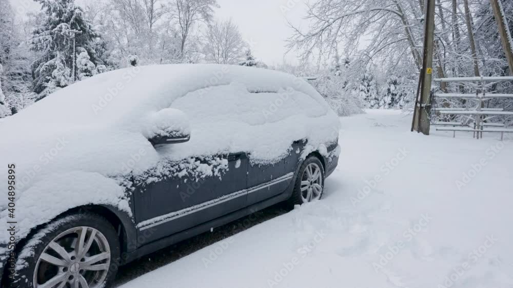 A black car being covered with the thick white snow during the winter season in the country A black car being covered with the thick white snow during the winter season in the country