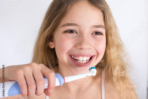 Young girl portrait with rotating-oscillating electric toothbrush isolated on white background. Oral hygiene and white teeth concept.
