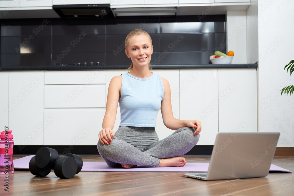 Woman using laptop and dumbbells for training at home