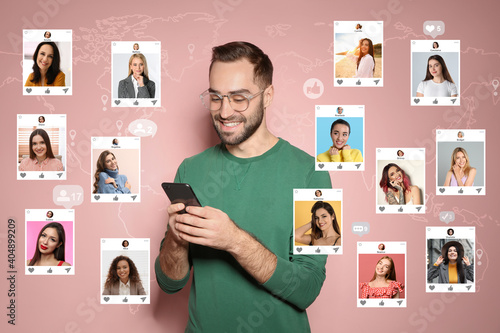 Photos Handsome man visiting online dating site via smartphone on pink background