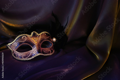 Photo of elegant and delicate gold Venetian mask over dark silk background