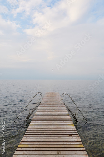 Pontile di legno con scalette su lago di Garda photo