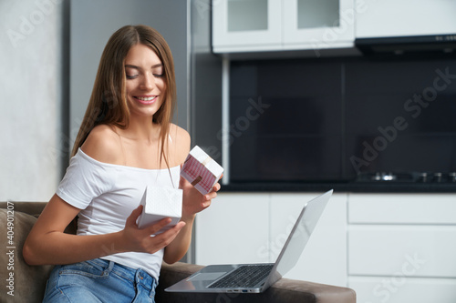 Lady sitting on sofa with laptop and unpacking birthday gift