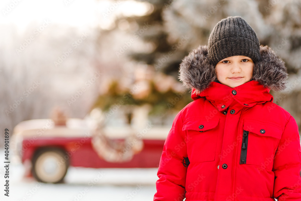 Seven-year-old boy in red down jacket looks into camera in winter Seven-year-old boy in red down jacket looks into camera in winter