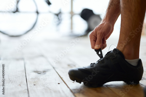 Young man putting on sports shoes before training at home