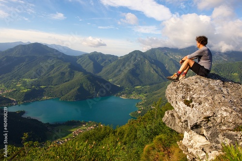 Wanderer am Fels mit Blick zum Ledrosee Italien