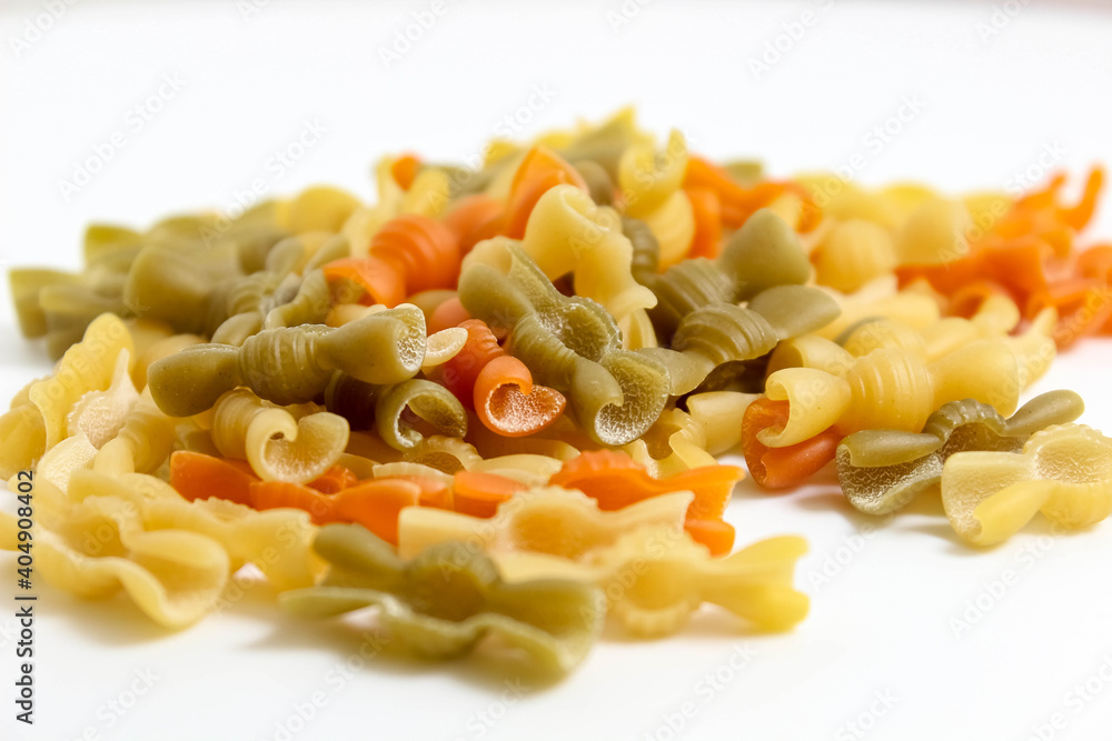 Multicolored macaroni close-ups fall from above on a white background.