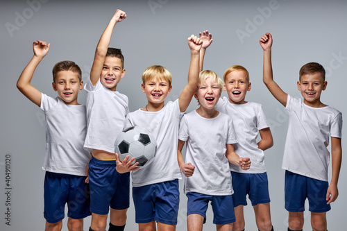 boys soccer team celebrating a victory after match, motivated children sports team rising hands up © Roman