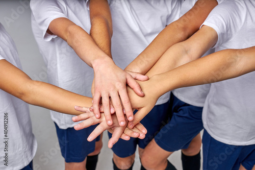 cropped team of young soccer players wish for good game  hold hands together  wearing uniform. football  sport concept. top view on hands