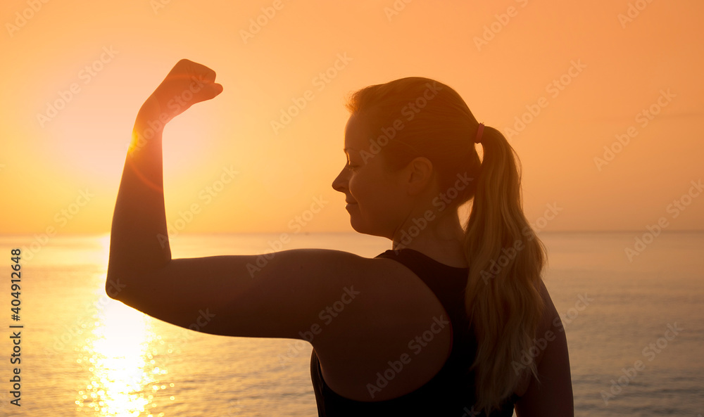 Silhouette of female athlete on sunset/sunrise seaside background, concept of endurance, strength, healthy lifestyle