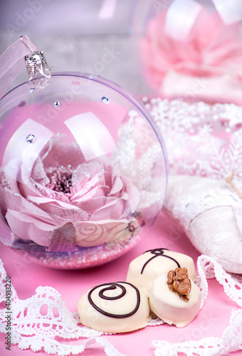 Christmass New Year decorations. Greeting card. White chocolate candy, Christmass ball. Tender pink and gray color.