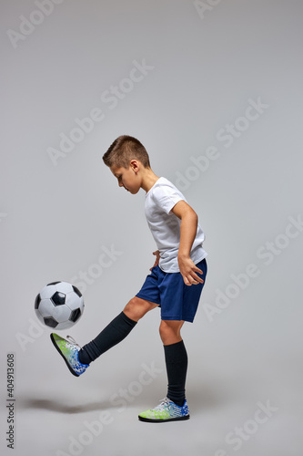 boy professionally training with soccer ball in studio, preparing for competition, game, wearing special uniform. isolated portrait