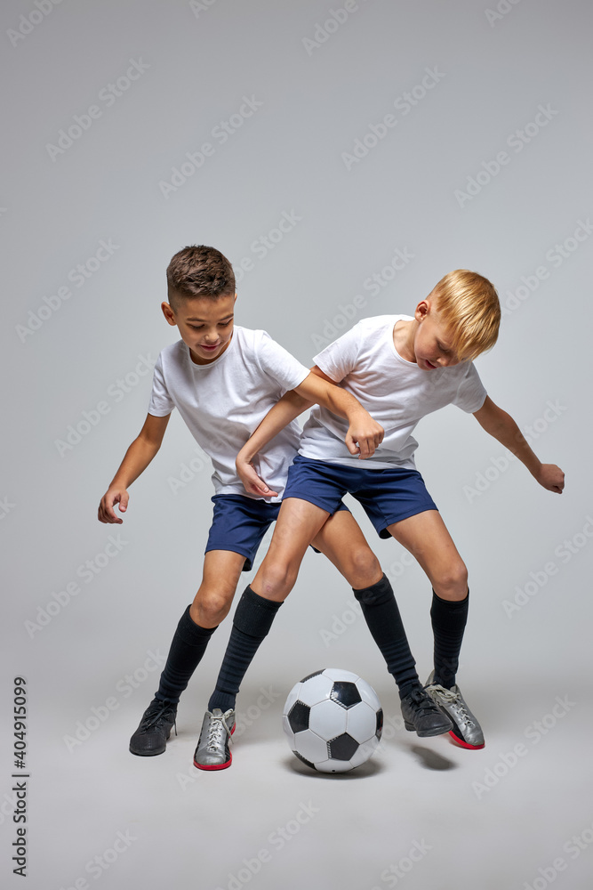 children soccer team on training, two boys practicing game with a soccer ball in studio. training football session for children on soccer camp. young boy improving dribbling skills children soccer team on training, two boys practicing game with a soccer ball in studio. training football session for children on soccer camp. young boy improving dribbling skills