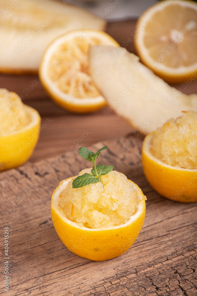 Melon and lemon fruit sorbet. Summer refreshing dessert in half of lemon fruit peel over on old wooden background. Melon and lemon fruit sorbet. Summer refreshing dessert in half of lemon fruit peel over on old wooden background.