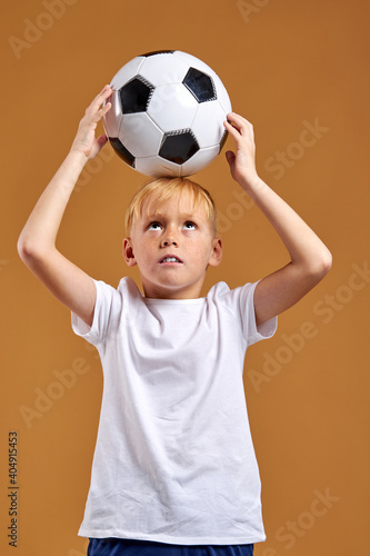 child boy holding soccer ball over head, enjoy sport activities. isolated portrait . football © Roman