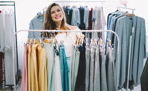 Cheerful woman choosing garments in shop