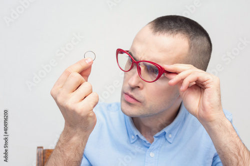 Concentrated man looks at his wedding ring  white background