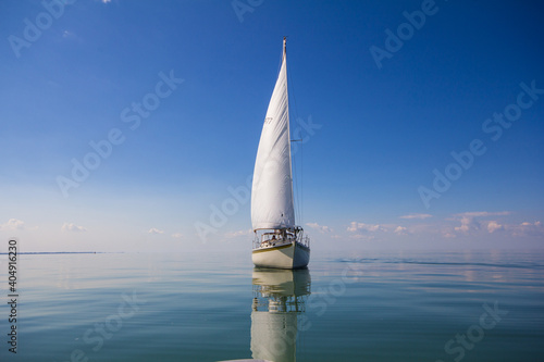Sailboat calm day with blue sky forward.