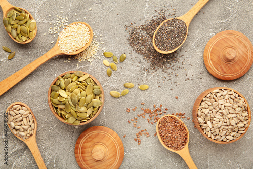 Healthy superfood: sesame, pumpkin seeds, sunflower seeds, flax seeds and chia on grey background. Seeds on spoon