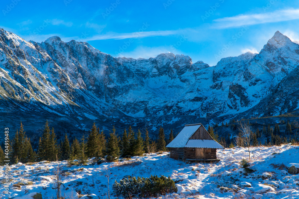 Beautiful, panoramic view to the snow covered mountains in tatras national park with house , zakopane poland. during a cold winter morning Mountain wooden cottage by the slopes.