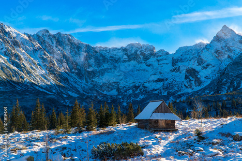 Beautiful, panoramic view to the snow covered mountains in tatras national park with house , zakopane poland. during a cold winter morning Mountain wooden cottage by the slopes.