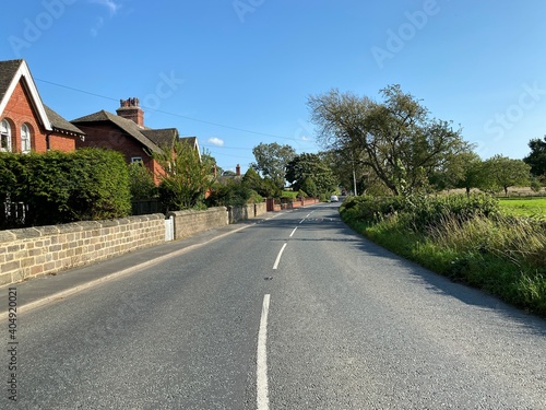 View along, Ripley Road, with stone walls, houses, and a blue sky in, Nidd, Knaresborough, UK