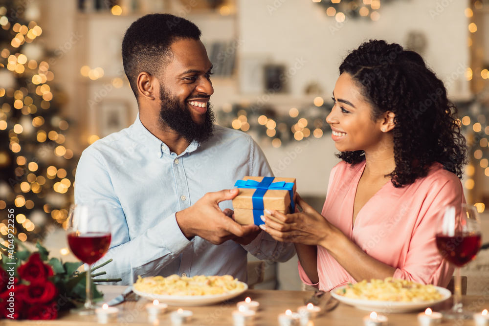 Young black man exchanging gifts with his happy woman
