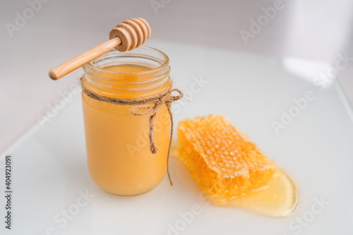 Honey pot with honey dipper and natural honeycomb .